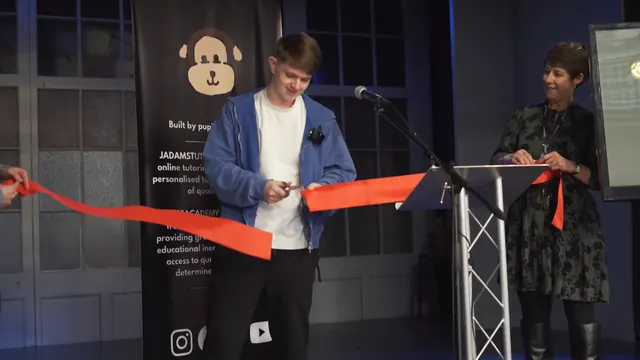 JADAMSTUTOR founder Joshua Adams cutting a red ribbon in front of a JADAMSTUTOR banner at an opening event